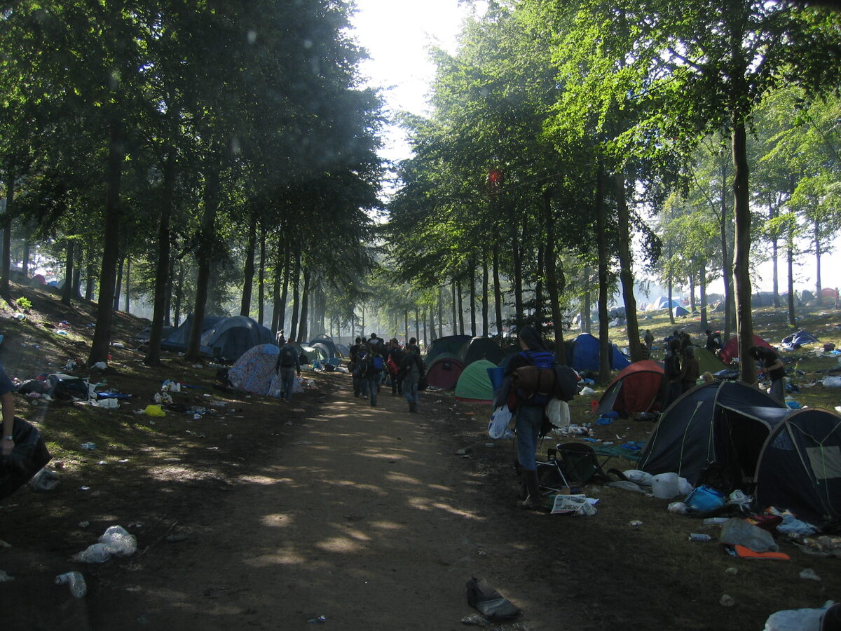 Path through the trees at the Leeds Festival campsite, littered after a big night
