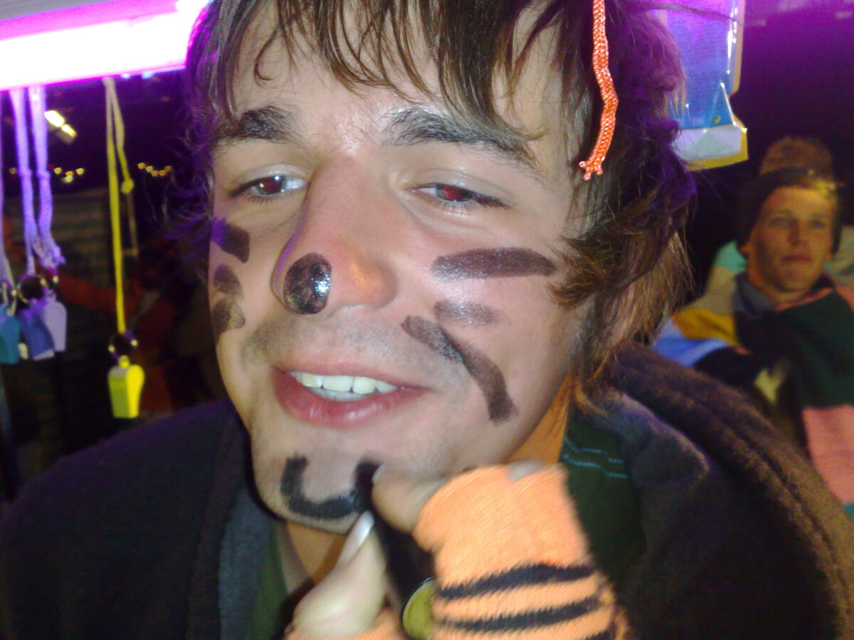 A festival-goer getting a black lipstick cat face painted on at the Willy Banjo stall