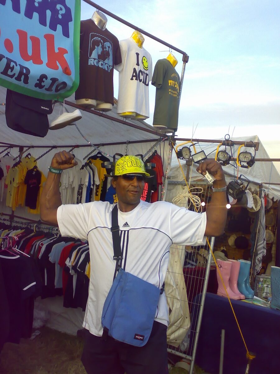 A trader flexing in front of the t-shirt stand