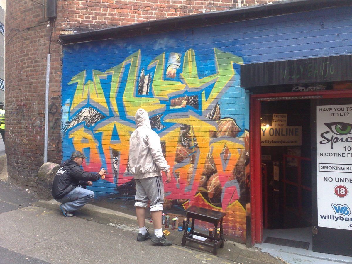 Polish graffiti artists painting the big WILLY BANJO piece outside the shop, 2008