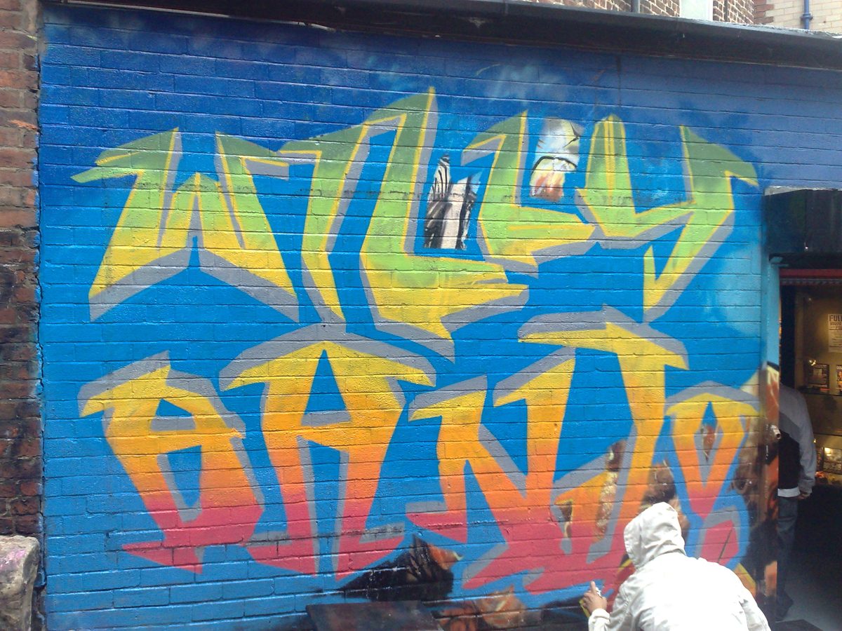 Finished yellow and orange WILLY BANJO graffiti piece on a blue wall, 2008