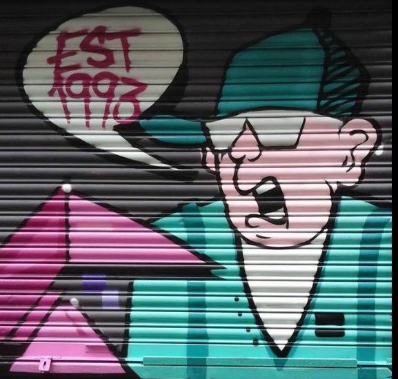 Cartoon character on the Willy Banjo shutter with an EST 1993 speech bubble