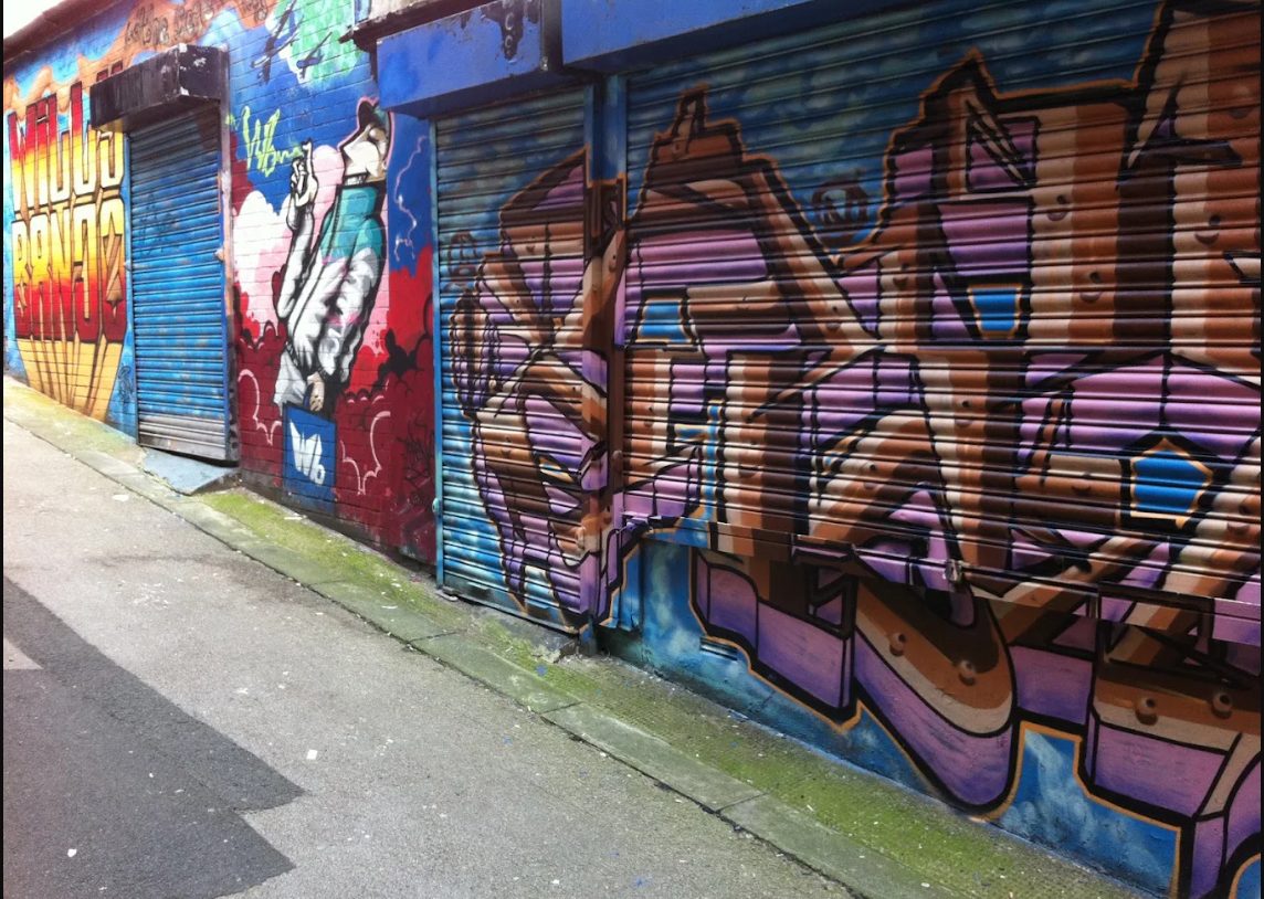 Purple and brown graffiti across the Willy Banjo shutters by Reasm One, Shawn Sharpe
